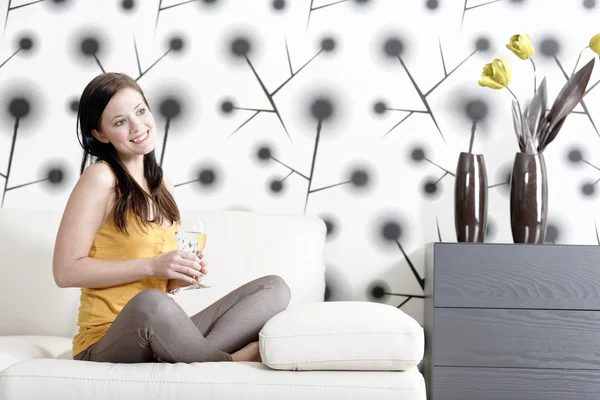 Woman relaxing on her sofa with a drink — Stockfoto