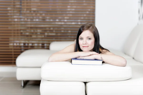 Kvinna liggande på soffan med en bok — Stockfoto