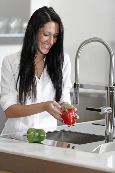 Woman rinsing peppers in a sink — Stock Photo, Image