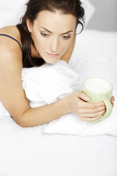 Mujer bebiendo en la cama — Foto de Stock