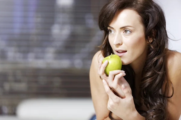 Frau liegt mit einem Apfel auf Sofa — Stockfoto