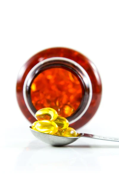 Capsules of fish oil on spoon with bottle — Stock Photo, Image