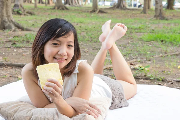 Chica joven con un sándwich en tela blanca en el parque —  Fotos de Stock