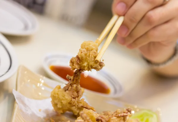 盘送达的酥炸的鱿鱼和筷子用一只手 — 图库照片