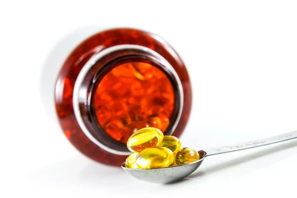 Capsules of fish oil on spoon with bottle — Stock Photo, Image