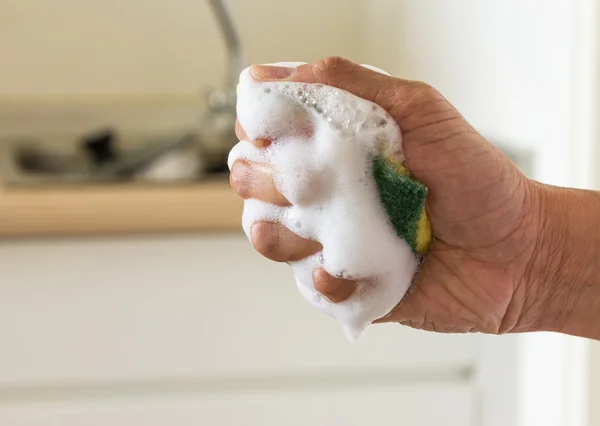 Sponge in squeeze hand with dishwashing liquid — Stock Photo, Image