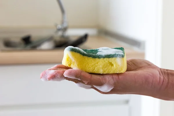 Губка в руке с жидкостью для мытья посуды — стоковое фото