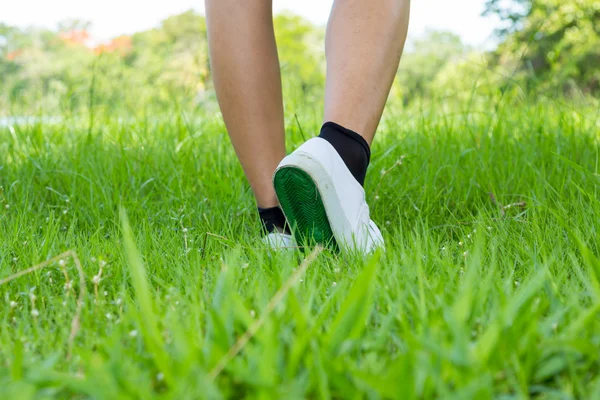 脚的运动鞋与前景草原上的一步 — 图库照片