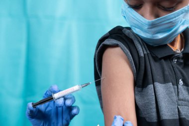 Maski, Hindistan - 26 Ekim 2021: Tıbbi maskeli genç çocuk Moderna Covid-19 veya Coronavirus çocuk aşısı yaptırıyor