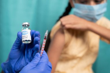 Maski, Hindistan - 26 Ekim 2021: Aşı şişesine odaklan - Tıbbi maskeli çocuk Pfizer 's Covid-19 ya da Coronavirus çocuk aşısı yaptırıyor