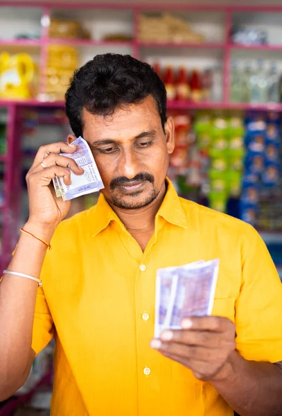 Retrato de Kirana preocupada o triste o comerciante de comestibles contando dinero en la tienda al por menor - concepto de baja o pérdida en los negocios, bancarrota y reembolso de préstamos. —  Fotos de Stock