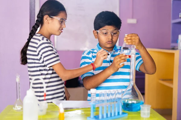 Primer plano de niños concentrados revisando o analizando quimicos sosteniendo el frasco mientras realizan experimentos en el laboratorio de química —  Fotos de Stock