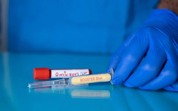 Έννοια του Booster shot για omicron covid-19 coronavirus μεταλλαγμένη διακύμανση δείχνει με την τοποθέτηση αναμνηστική σύριγγα πυροβολισμό ή ένεση μπροστά από δείγμα αίματος omicron. — Φωτογραφία Αρχείου