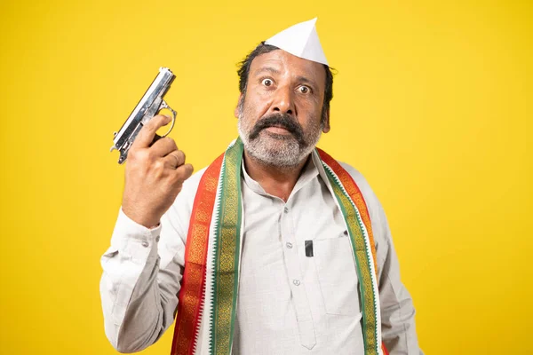 Politicien avec pistolet à la main regardant la caméra sur fond jaune concept de menace criminelle et politique. — Photo