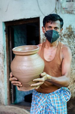 Pot maker with medical face and pot in hand looking at camera during coronavirus or covid-19 pandemic outbreak as safety measures.