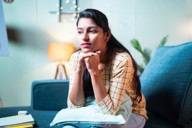 Deep thinking sad young girl at home - concept of focused, unhappy and stressed lifestyle