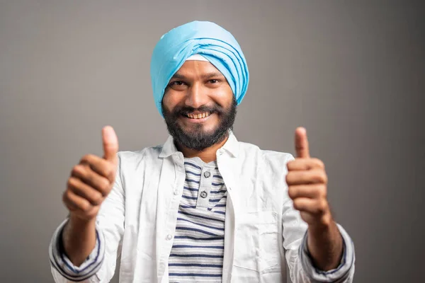 Happy Young indian sikh man showing thumbs up hand gesture by looking at camerea - Concept of self-confident, positive emotion and successful people. — стоковое фото