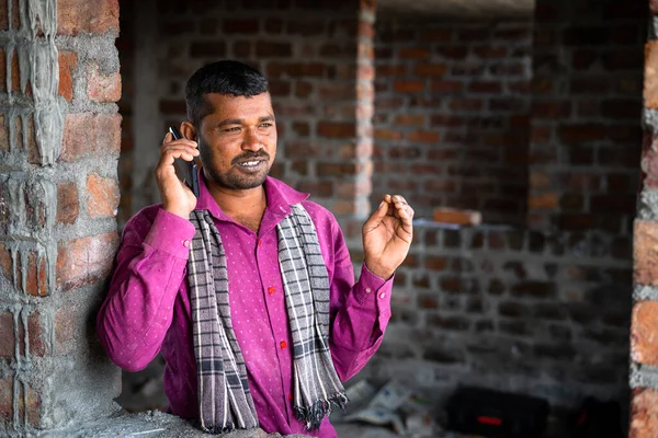 Gelukkige glimlachende bouwvakkers in gesprek op mobiele telefoon - concept van communicatienetwerk en -technologie — Stockfoto