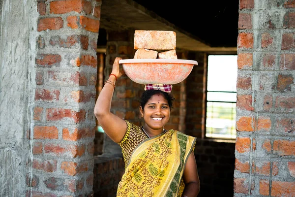 Hardwerkende Indiase lachende vrouwen met stenen op het hoofd op zoek naar camera - concept van de dagelijkse inzet levensstijl, positieve emotionele en vrouw empowerment. — Stockfoto