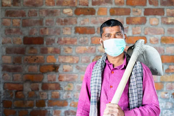 Уверенный строитель с медицинской маской, смотрящий в камеру на рабочем месте - концепция возвращения к работе после пандемии коронавируса covid-19 с мерами безопасности — стоковое фото