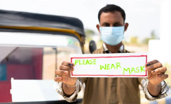Сосредоточьтесь на руке, авто рикша водитель с медицинской маской отображения лица, пожалуйста, носить знак маски, глядя на камеру для пассажира, чтобы защитить от коронавируса или ковид-19 инфекции в качестве мер предосторожности. — стоковое фото