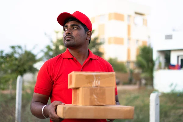 Bezorger met kartonnen dozen in de hand op zoek naar adres van de klant - concept van het zoeken naar consument thuis en e-commerce koerier service — Stockfoto