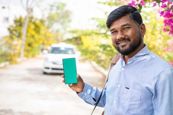 Sonriente pasajero joven que muestra el teléfono móvil de pantalla verde mirando a la cámara - concepto de taxi en línea o servicio de reserva de taxi, publicidad de aplicaciones y ofertas promocionales. —  Fotos de Stock