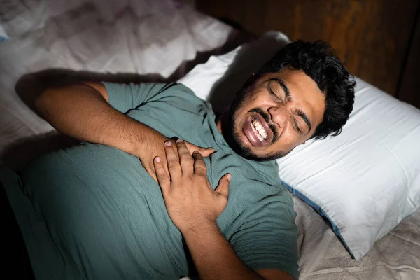 Jeune Indien a eu une douleur thoracique soudaine pendant un sommeil profond la nuit concept de soins de santé, la maladie et les douleurs cardiaques. — Photo
