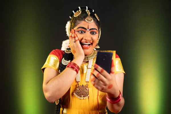 Excited Bharatnatyam dancer by seeing as winner on mobile phone - concept of online shopping e-commerce offers, final round selection and technology — Stock Photo, Image