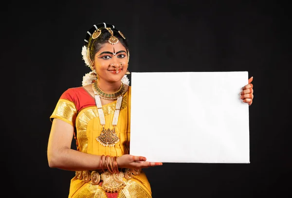 Indiaas mooi bharatanatyam meisje tonen wit leeg bord of bordje door te kijken naar de camera - concept van aankondiging, reclame en indiaanse cultuur — Stockfoto