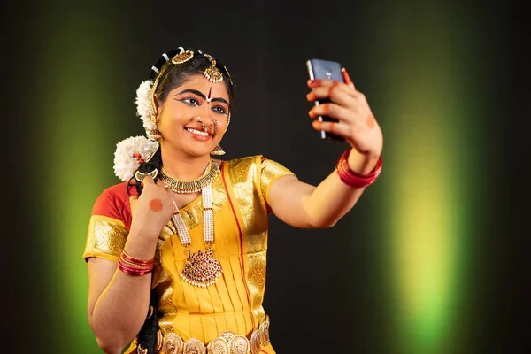 Portrait de jeune fille en costume de danseuse Bharatnatyam prenant selfie sur téléphone portable concept de partage des médias sociaux, passe-temps et la technologie. — Photo