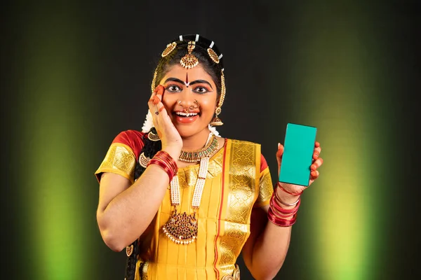 Portrait de la danseuse heureuse excitée Bharatnatyam montrant un téléphone portable à écran vert en regardant la caméra sur scène - concept d'offres de shopping fétivales, vêtements traditionnels et publicité pour les applications — Photo