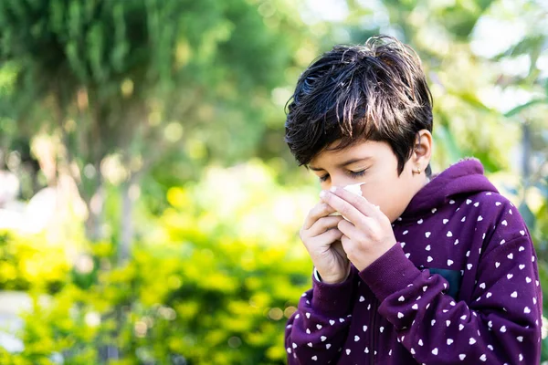 Niño enfermo estornudando en el parque durante el invierno - concepto de enfermedad estacional de invierno, gripe e infección —  Fotos de Stock