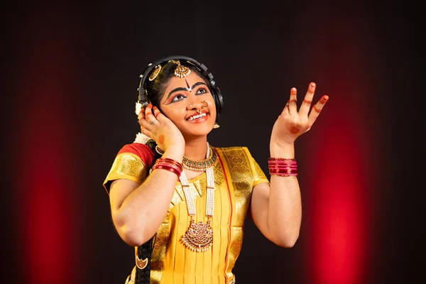 Genieten van de Indiase bharatanatyam danser luisteren favoriete lied op hoofdtelefoon op het podium - concept van ontspanning, klassieke danser en entertainment. — Stockfoto