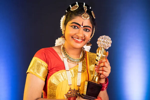 Gelukkig glimlachende bharatanatyam danser tonen winnaar trofee door te kijken naar de camera - concept van succesvolle, prestatie, trots en indiaanse cultuur — Stockfoto