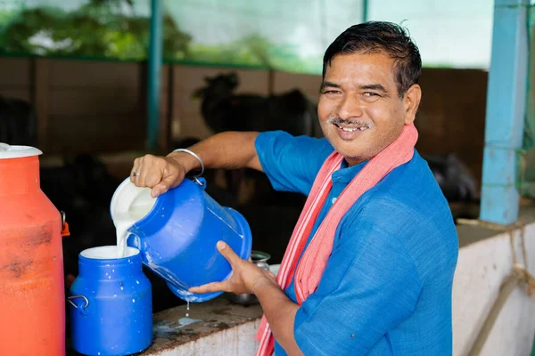 Gelukkige glimlachende melkveehouder bezig met werken terwijl hij naar de camera kijkt - concept van melkproductie agri busines, landelijk India, groei en landbouw — Stockfoto