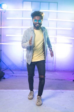 Genç adam sahnede yavaş çekim ya da robotik an olarak kameraya bakarak dans ediyor. Eğlence, hobi ve profesyonel dansçı kavramı..