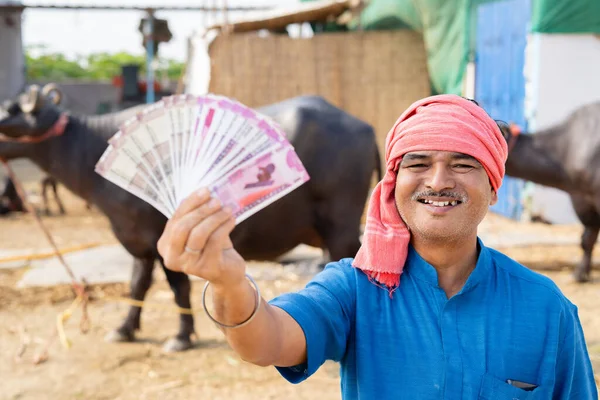Zelfverzekerde melkveehouder die geld in Indiase valuta toont door naar de camera te kijken - concept van inkomsten, bankieren en bedrijfswinst — Stockfoto