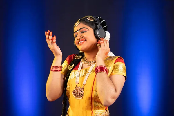 Profiter de danseuse indienne bharatanatyam en écoutant des chansons sur écouteurs sur scène concept de détente, de soulagement du stress et de divertissement. — Photo