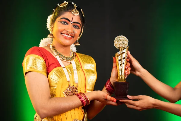 Un danseur bharatanatyam excité reçoit le trophée de la compitation dansante en remerciant - concept de réussite, de réussite, de culture traditionnelle fière et indienne. — Photo