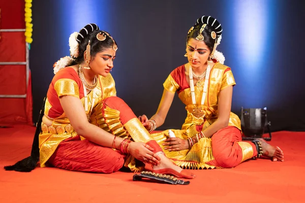 Vriend helpen terwijl Bharatnatyam danser die lijden aan been of enkel letsel tijdens het dansen op het podium - concept van traditionele dansers, saamhorigheid en veiligheid. — Stockfoto