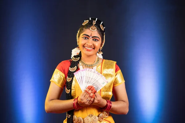Індійська посміхнена танцівниця Бхаратанатьям з індійськими грошовими купюрами, дивлячись на камеру - концепцію хаббі, фінансової свободи та банкінгу.. — стокове фото
