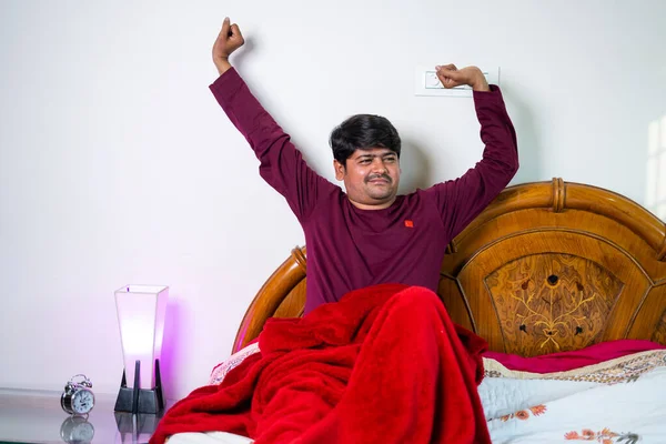 Le jeune homme se réveille le matin en étirant les bras sur la chambre à coucher concept de rafraîchissement, mode de vie sain et sommeil confortable — Photo