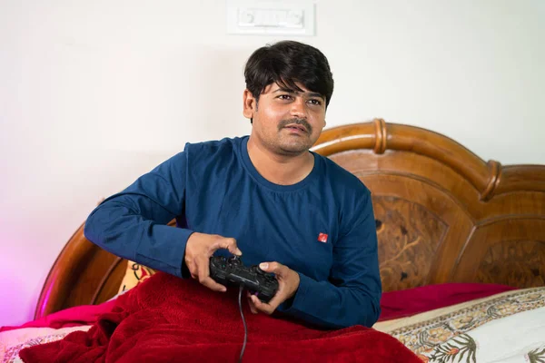 Jeune homme jouant jeu de vidoe sur le lit pendant la nuit avant de dormir concept de dépendance au jeu, divertissement et détente — Photo