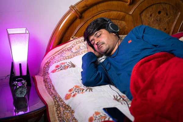 Jeune homme dormant en portant un casque pendant la nuit - concept de relaxation, de pleine conscience et de thérapie pour l'insomnie — Photo