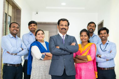 Ofiste kameraya bakarak kollarını kavuşturmuş çeşitli Hintli şirket çalışanları - takım çalışması, işgücü, iş geliştirme ve işbirliği kavramı.