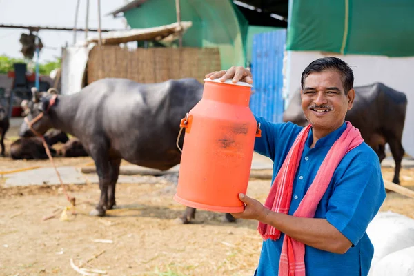 Milk dairy farmer holding milk container by looking at camera - concept of advertisement, agribusiness and successful milk production