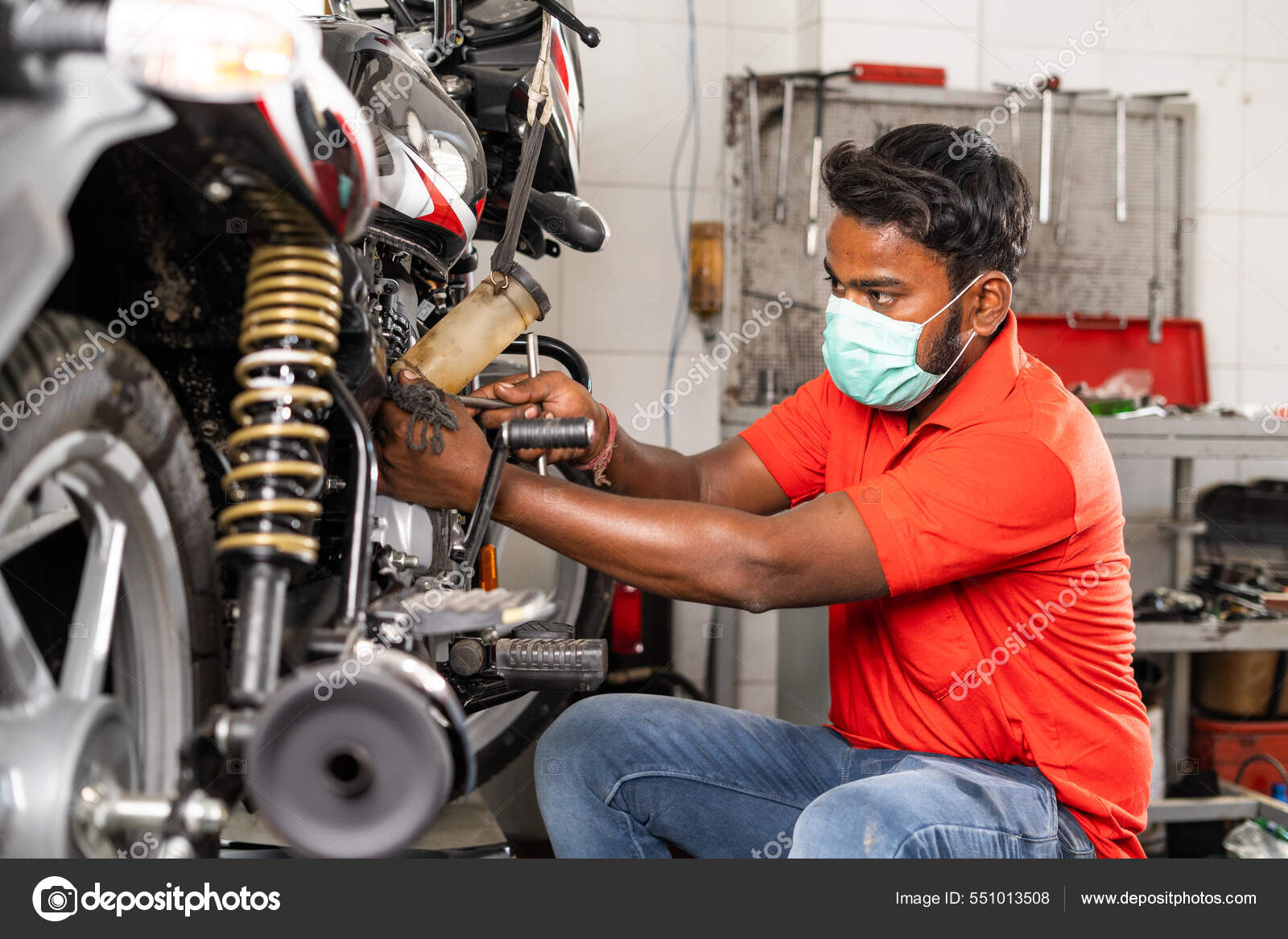 Motorbike mechanic busy repairing bike at garage with medical face