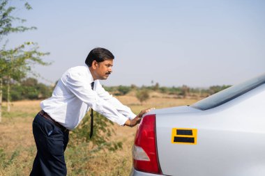 Sıcak ve güneşli bir günde, iş adamının bozuk arabayı itmesi - petrol krizi, talihsizlik ve hüsran kavramı