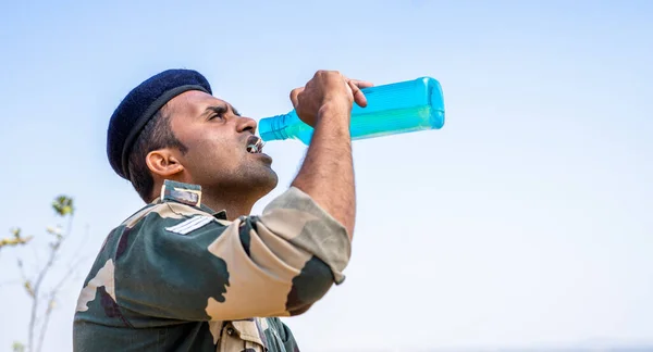 Spragniony żołnierz pijący wodę podczas gorącego słonecznego dnia na szczycie góry - koncepcja przerwy, relaksu i letniej fali upałów. — Zdjęcie stockowe